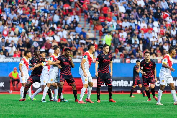Juan Luis Pérez, el penúltimo de Herediano, marca por la espalda a uno de los jugadores de los Xolos. (