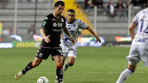 Ariel Rodríguez, a punto de pasar la bola ante el asedio en la marca de Sebastián Castro. (