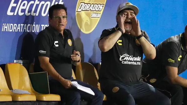 García, sentado a la par de Diego Maradona, en un partido de Dorados. (