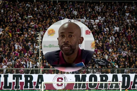 Paulo Wanchope en conferencia y la afición morada de fondo.