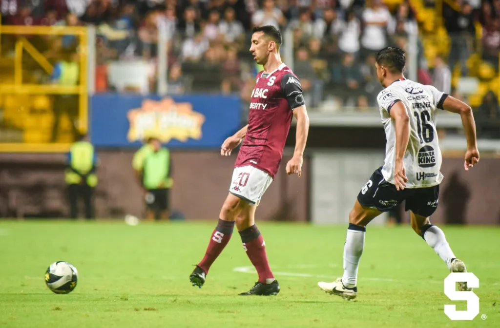 Mariano Torres pasa la bola antes de que llegue la marca de Christian Martínez. (Foto: Saprissa)