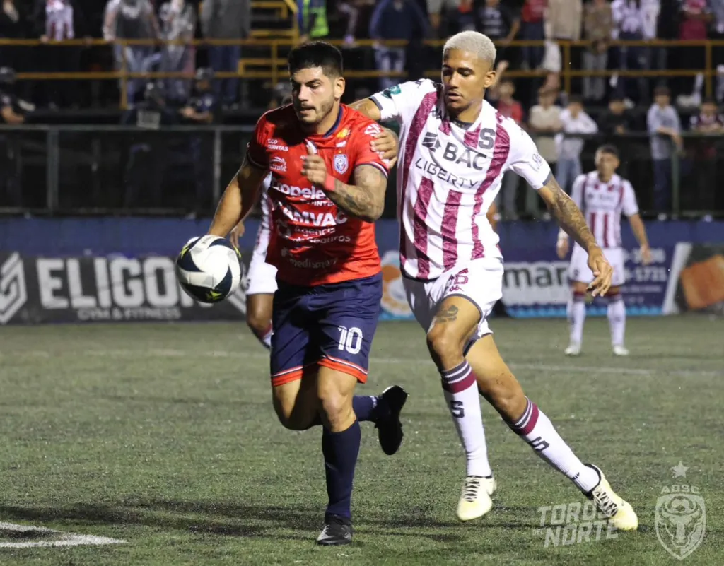 Gabriel Leiva, ahora refuerzo de Liberia, es marcado por Eduardo Anderson en el empate 2-2 entre San Carlos y Saprissa por la semifinal de ida. (Foto: ADSC)