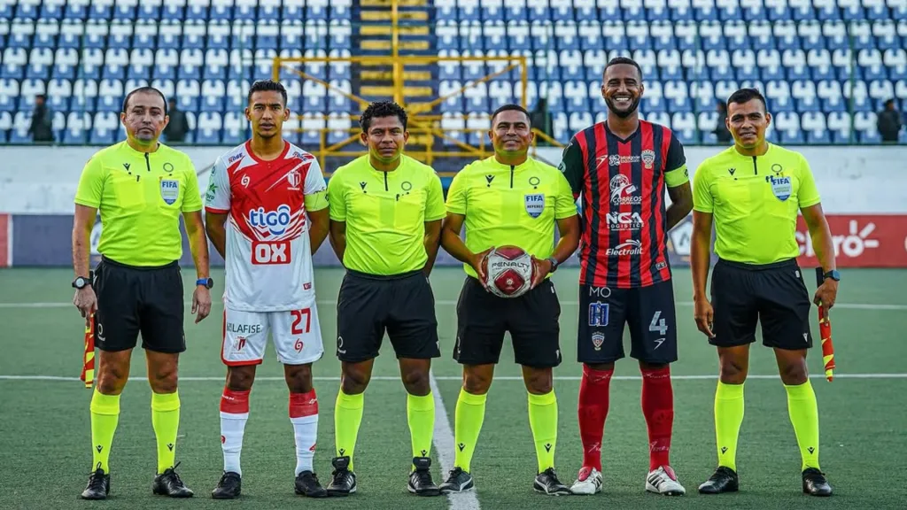 En la foto aparecen Nitzar Sandoval, sosteniendo la bola, y Enmanuel Aguirre, con la bandera en el costado derecho. (Foto: Liga Primera)